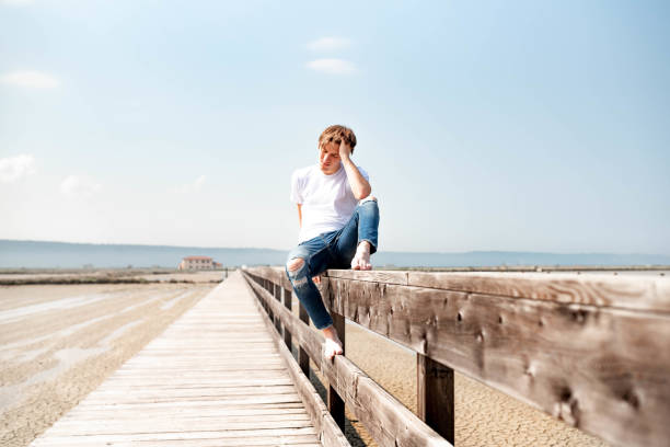istock Young man sitting on a wooden fence 1155962903