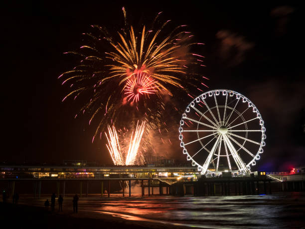 noria giratoria y competición internacional de fuegos artificiales en la playa de scheveningen, países bajos - ferris wheel flash fotografías e imágenes de stock