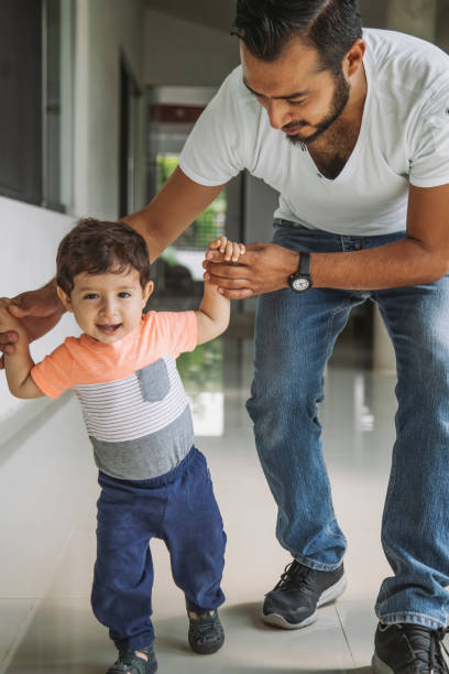 istock Mexican dad helping his baby boy take his first steps, learning to walk 1155965905