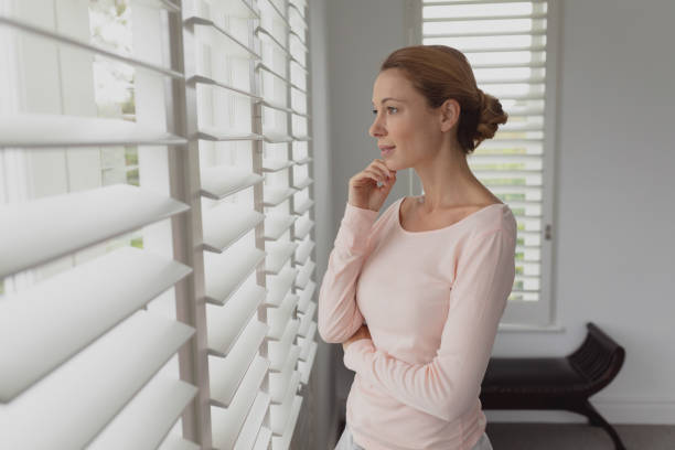 istock Beautiful woman looking outside through window 1155966180