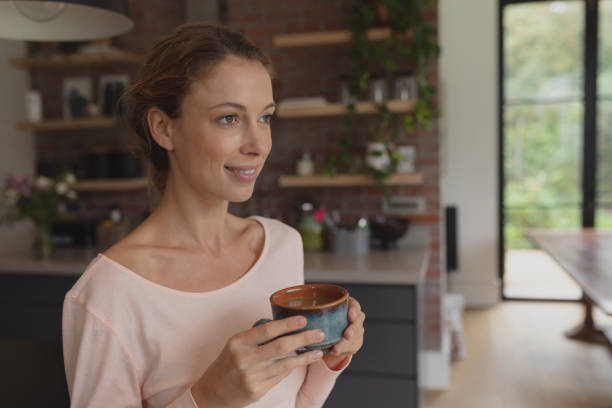 istock Woman holding coffee cup in kitchen 1155970498