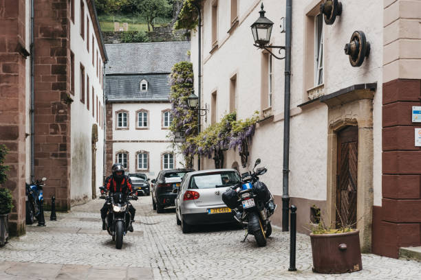 Motorcyclist on a narrow cobblestone street in Vianden, Luxembourg. Vianden, Luxembourg - May 18, 2019: Motorcyclist on a narrow cobblestone street in Vianden, town in Luxembourgs Ardennes region known for the centuries-old hilltop Vianden Castle. vianden stock pictures, royalty-free photos & images