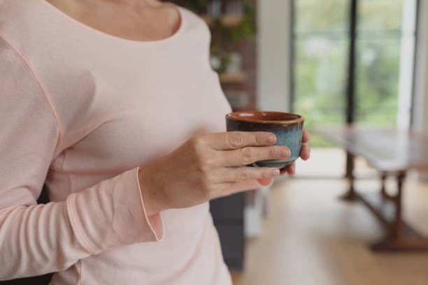 istock Woman holding coffee cup in kitchen 1155971041