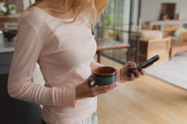 istock Woman holding coffee cup and using mobile phone 1155971103