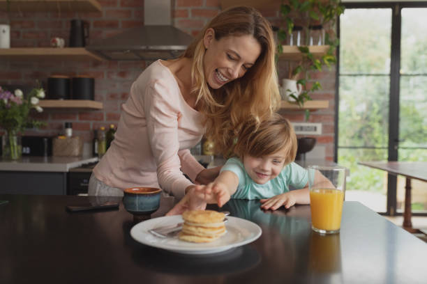 istock Mother serving food to her son at dining table 1155971236
