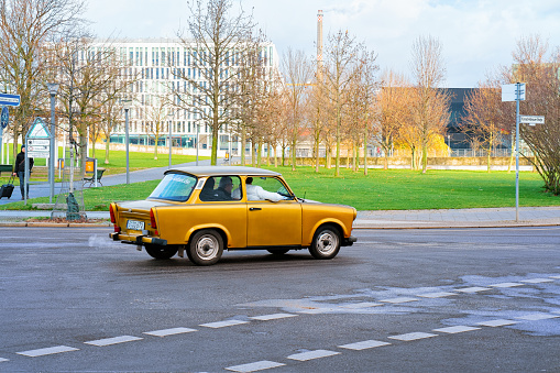 Berlin, Germany - December 8, 2017: Yellow old Trabant car on the road in Berlin Mitte in City centre. Modern building architecture, old transport in Germany in Europe.