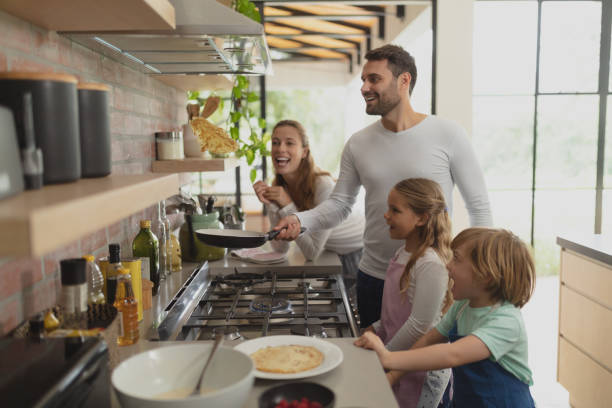 Family preparing food in kitchen at home Front view of happy Caucasian family preparing food in kitchen in a comfortable home stove stock pictures, royalty-free photos & images