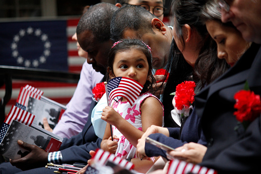 Philadelphia, PA, USA - June 14, 2019: The daughter of a immigrant holds an American flag while she joins her mother's naturalization ceremony on Flag Day at the historic Betsy Ross House in Philadelphia, Pennsylvania.