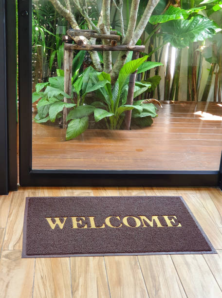 istock Welcome text on brown carpet in front of exit to garden 1155978477