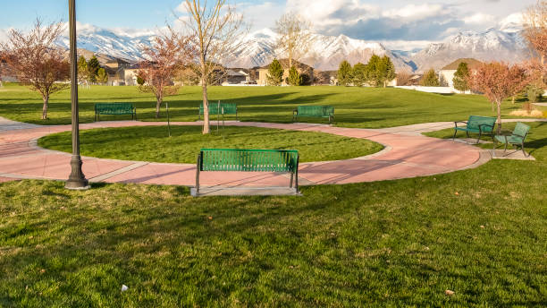 istock Panorama frame Green benches around a circular pathway on a park with trees and lamp posts 1155982720
