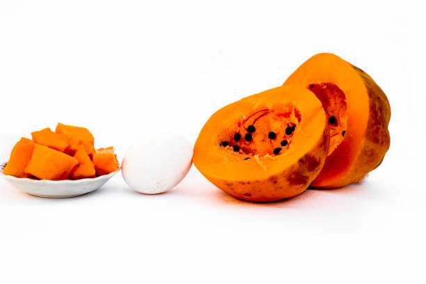 Papaya face mask isolated on white i.e. Papaya pieces well mixed with egg white in a transparent glass bowl along with entire raw ingredients.