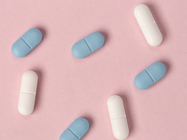 istock White and blue tablets on a pink background. View from above 1155985352