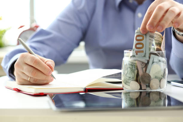 istock Male hand depositing some extra money in future needs 1155986695