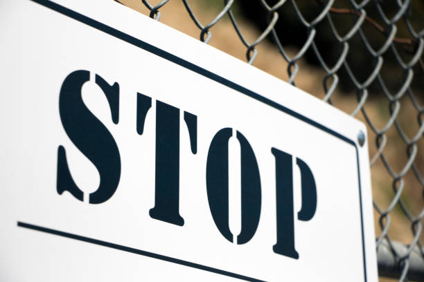 istock 'STOP' sign affixed to chain link fence 1155987771