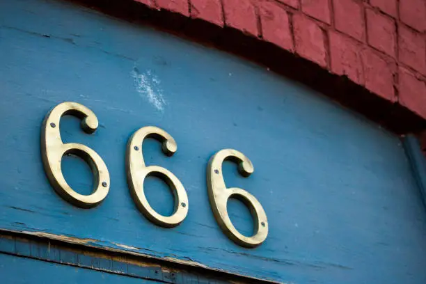 Closeup of brass street address numbers '666' above a doorway