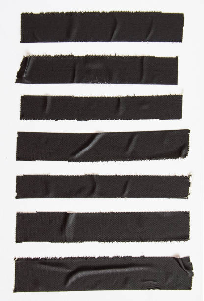 Crumpled pieces of black matte cloth gaffer tape on white paper background. stock photo