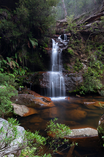 Beautiful ushland oasis with pretty waterfall tumbling into rock pool surrounded by Australian bushland