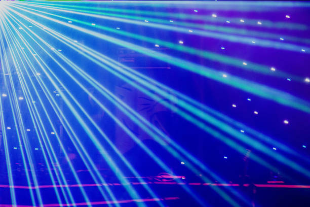 istock Bright nightclub purple, white, blue laser lights cutting through smoke machine smoke making light and rainbow patterns on the dance floor with bokeh in the background. Mardi Gras inspiration 1155997607