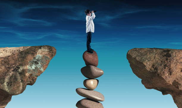 istock Kid looking through binoculars on a stack of stones in a gap between two rocks. 1156007867