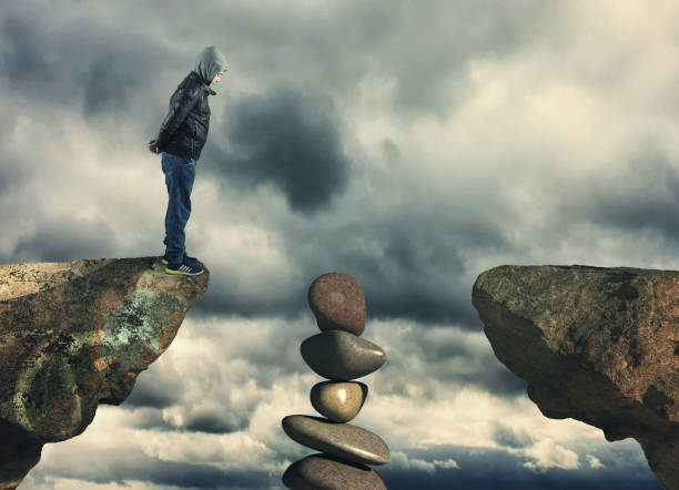 istock Kid standing at edge of a mountain peak looking down. 1156008418