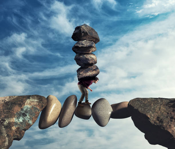 istock Man carries a stack of stones on a unstable path between two mountain peaks. 1156008436