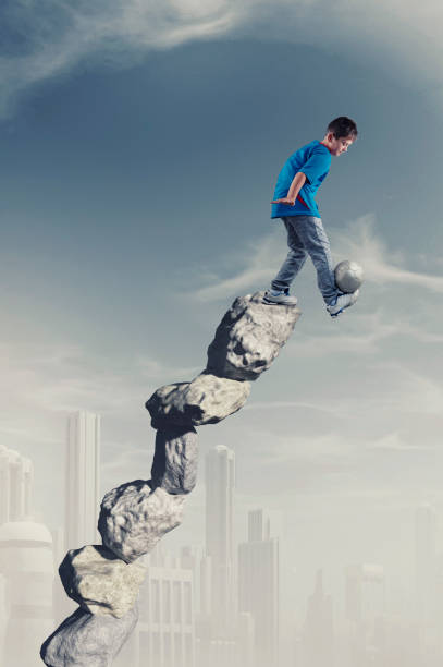 istock Kid playing football on a stack of stones. 1156008522