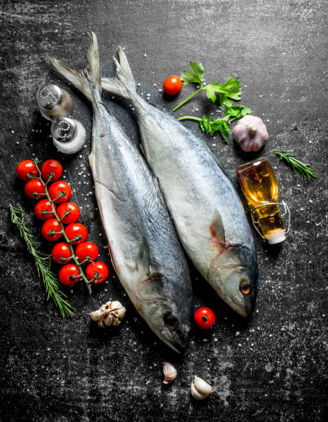 istock Raw fish with tomatoes on branch, greens and oil. 1156011608