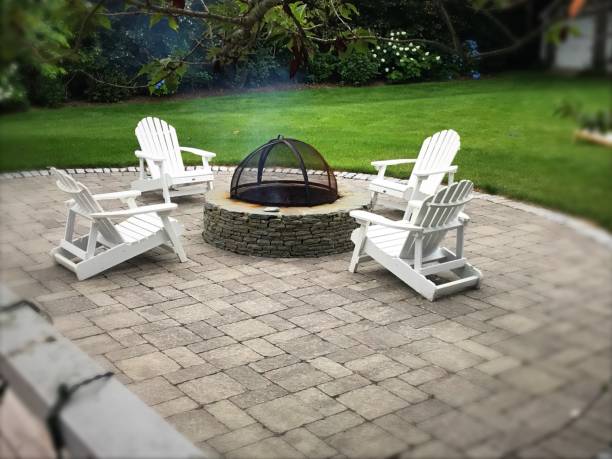 Chairs around a Firepit Four chairs sit around a backyard fire pit on a summer evening. fire pit photos stock pictures, royalty-free photos & images
