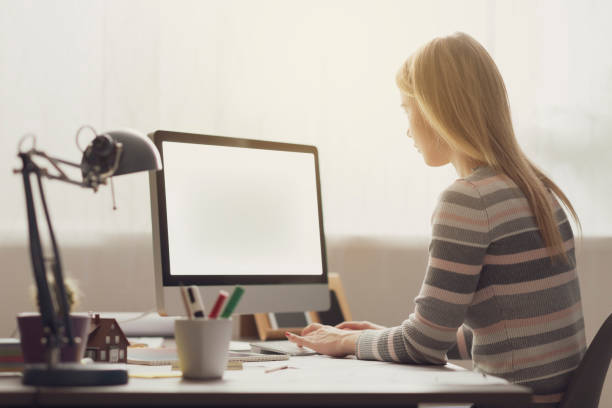 istock Young woman sitting at desk and typing 1156013149