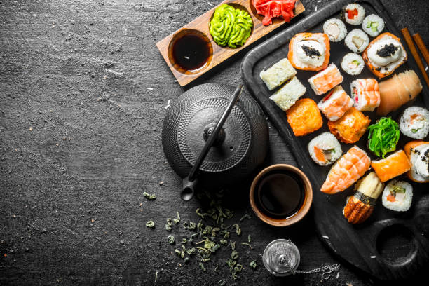 traditionelles japanisches sushi und brötchen mit grünem tee in der teekanne. - seafood prepared shrimp prawn avocado stock-fotos und bilder