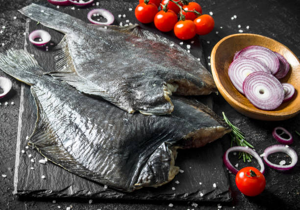 istock Raw fish flounder with chopped onions, tomatoes and rosemary. 1156025450