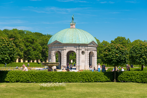 Temple of Diana in the colorful gardens of Hofgarten park in the centre of Munich Germany\n\nPeople clearly visible walking through the park