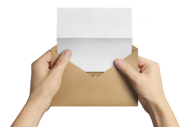 istock Hand holding an open brown envelope with a blank folded paper inside, on white 1156039027