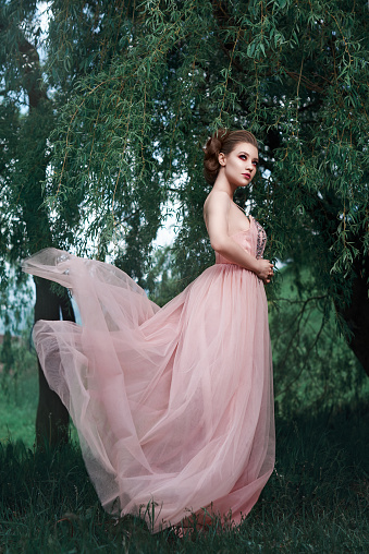 so beautiful fashion model in nature posing in fluffy pink dress, feeling attractive.