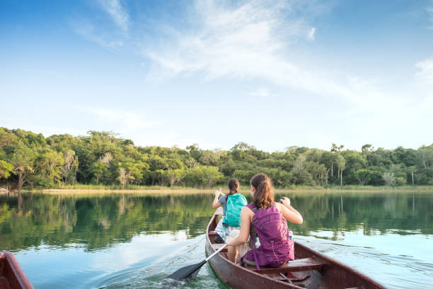 prospettiva in prima persona delle sorelle con zaini canoa nel lago - water sport lake canoe canoeing foto e immagini stock