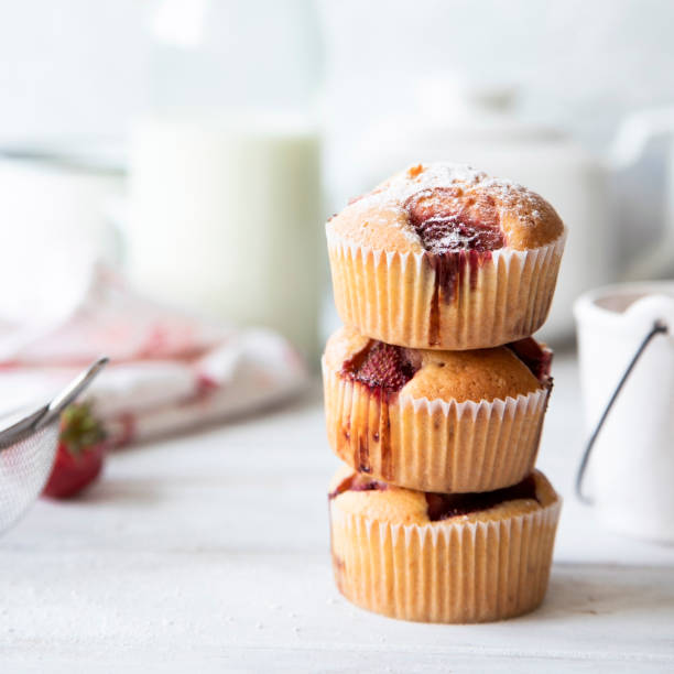 istock Frosted strawberry muffins on white table. 1156051165