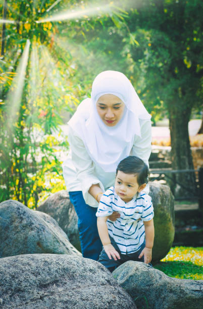 istock Mother Wearing Hijab While Holding Son By Rocks In Park 1156052600