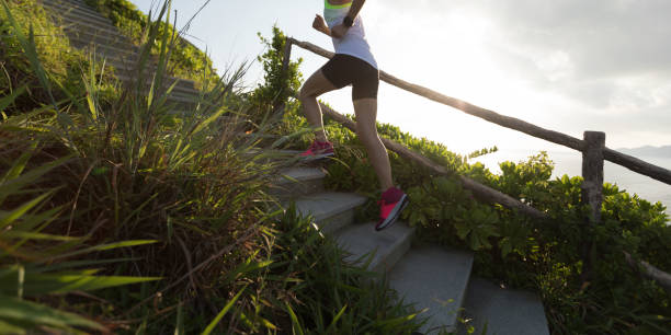 istock Determined woman running up on seaside mountain stairs 1156057171