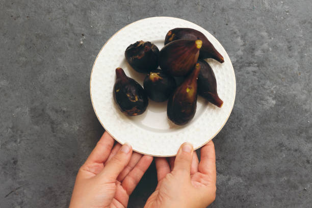 istock closeup hand holding a plate of fresh figs 1156058722