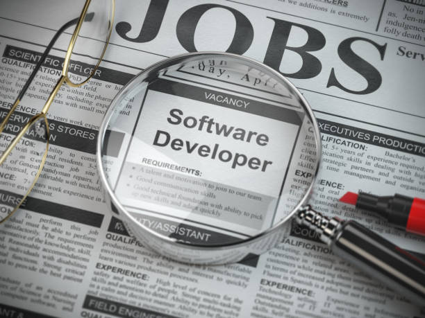istock Software developer vacancy in the ad of job search newspaper with loupe. 1156063131