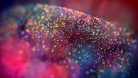a cloud of multicolored particles in the air like sparkles on a dark background with a small depth of field. beautiful bokeh light effects with colored particles. background for holiday presentations