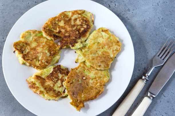 istock zucchini pancakes on a plate, vegetable pancakes, fork, knife on a gray background, top view, 1156063526