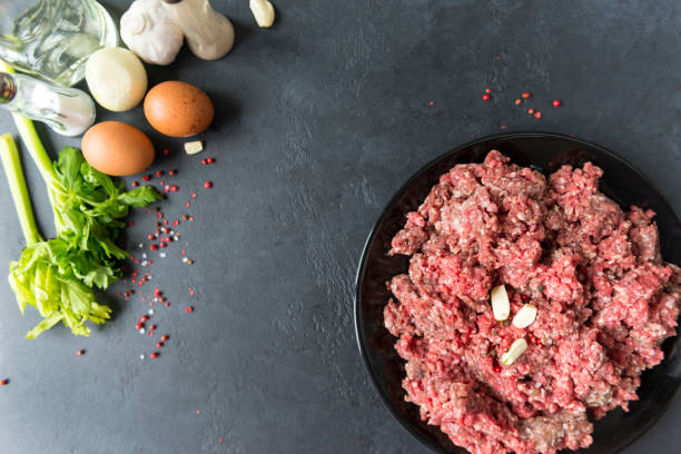 istock raw minced meat with garlic cloves on a plate, spices, eggs, celery, onions on  a black background, pork 1156063685