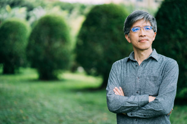 istock Asian man with eyeglasses standing arms crossed in park 1156064672