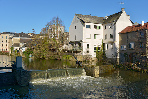 Little waterfall and buildings on the bank of river Sarthe at Alençon of the Lower Normandy region in France