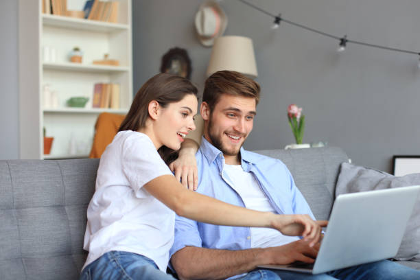 istock Young couple doing some online shopping at home, using a laptop on the sofa. 1156068738
