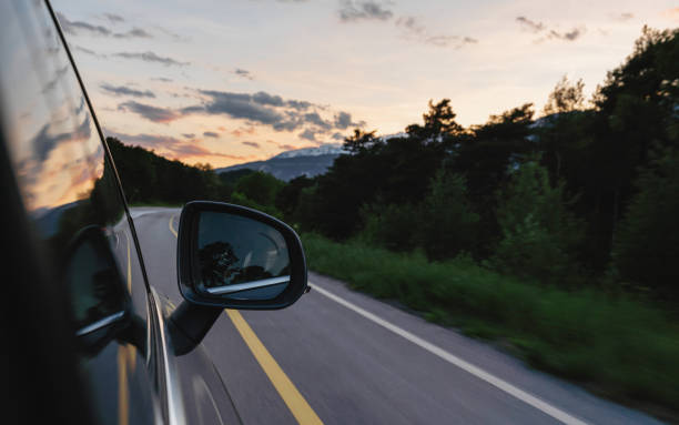istock Driving on country road in summer at sunset, side wing mirror view 1156073548