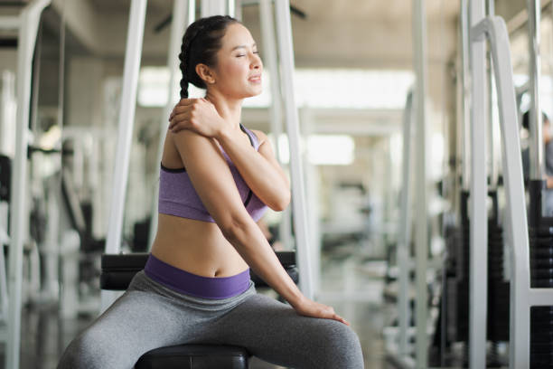 若い女性はジムでトレーニング中に肩に筋肉痛を持っています。フィットネス、筋肉痛の概念での事故ウェイトトレーニング。 - human muscle the human body people muscular build ストックフォトと画像