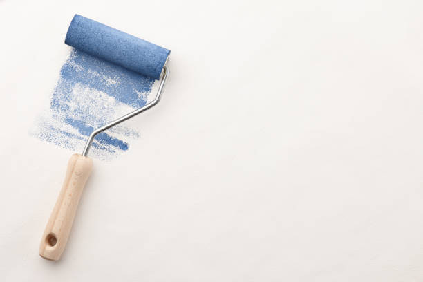 istock Roller with blue paint on wallpaper background 1156079386