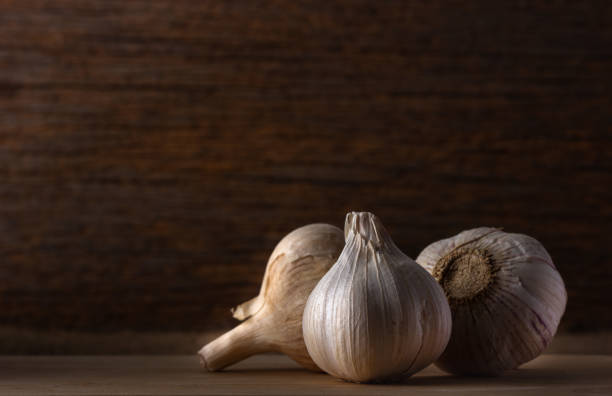 istock group of garlic head on wooden background , low light. 1156082553